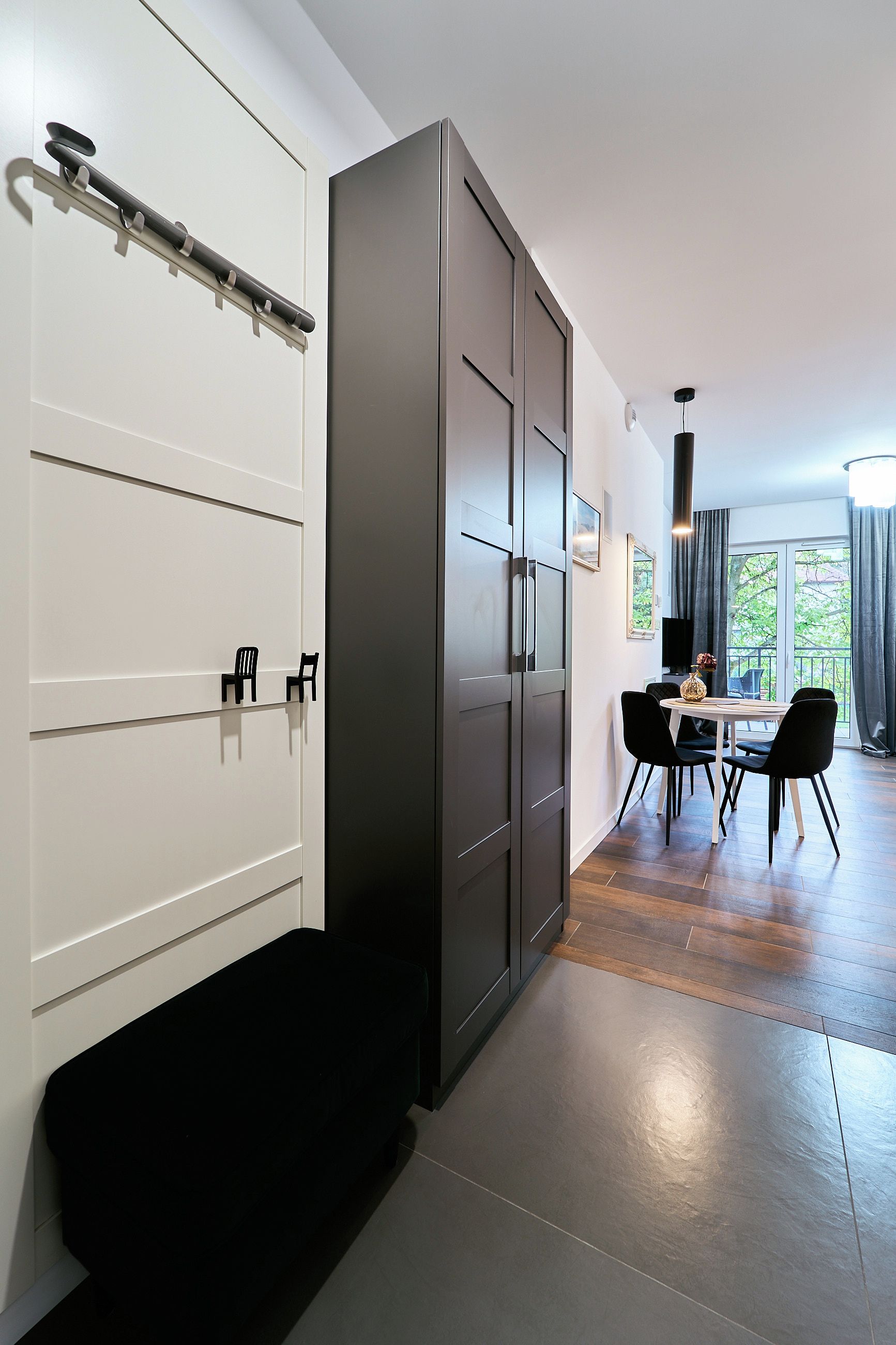 A modern interior with a dining area, a black bench, and a large cabinet.