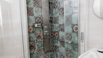 Un baño moderno con cabina de ducha de vidrio, un lavabo blanco y azulejos decorativos.