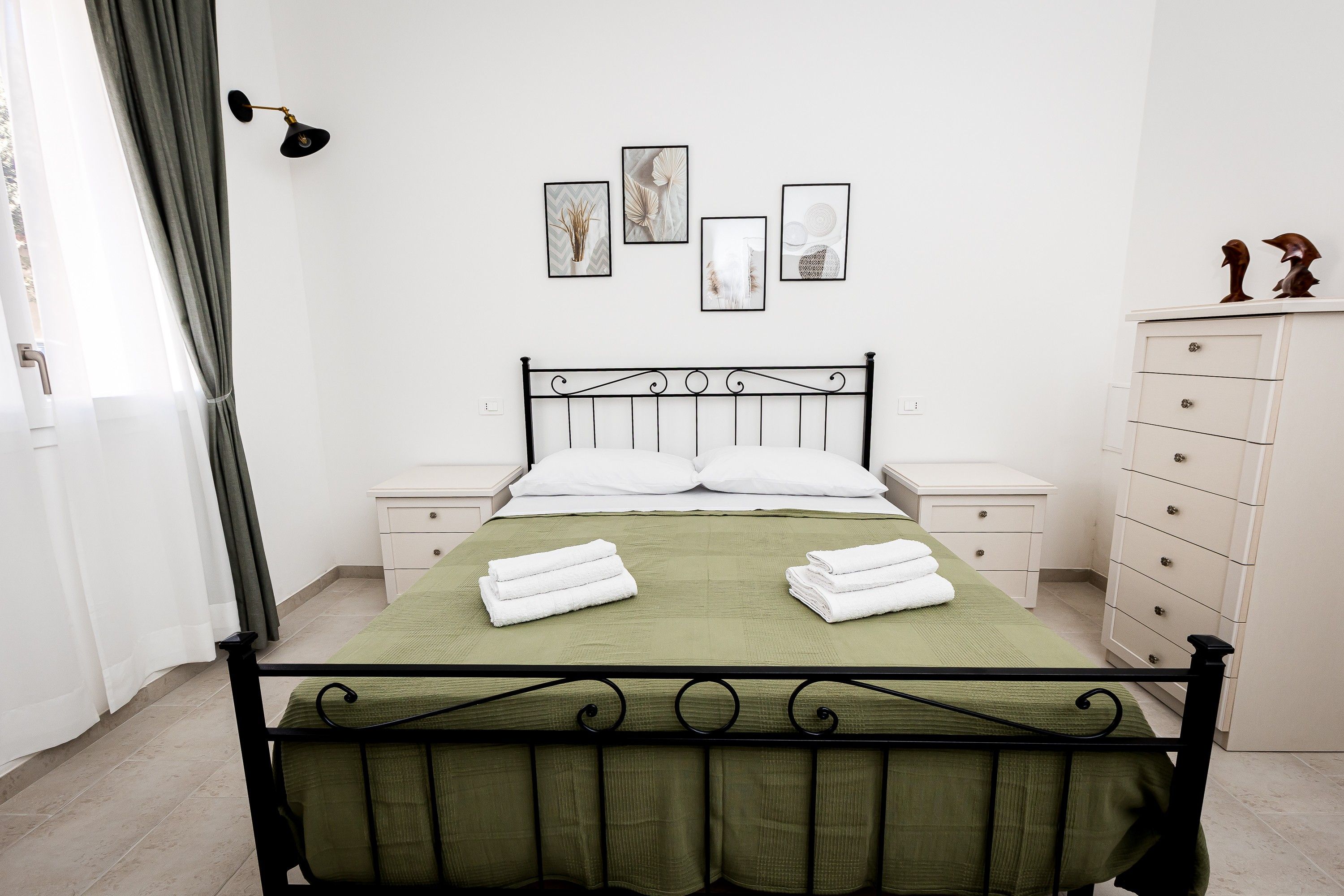 Un dormitorio ordenado con cama, mesitas de noche, cómoda y decoración en la pared.