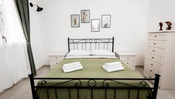 Un dormitorio ordenado con cama, mesitas de noche, cómoda y decoración en la pared.