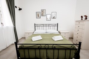 Un dormitorio ordenado con cama, mesitas de noche, cómoda y decoración en la pared.