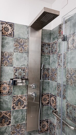 Dusche mit Handbrause und Regendusche, umgeben von dekorativen Fliesen.