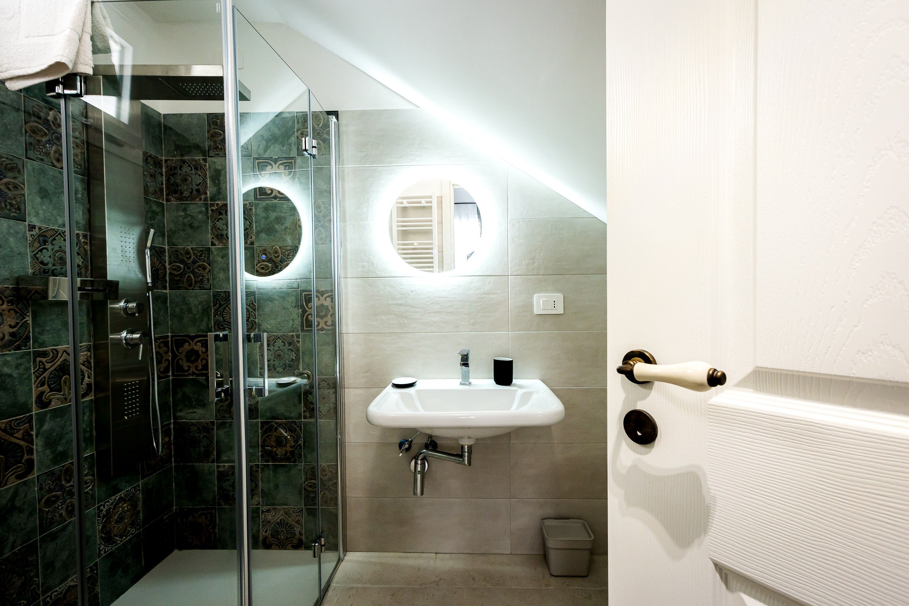Une salle de bain avec une douche à parois de verre, un lavabo avec un miroir et un porte-serviettes.