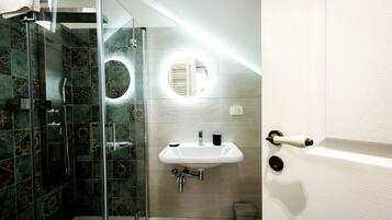 Une salle de bain avec une douche à parois de verre, un lavabo avec un miroir et un porte-serviettes.