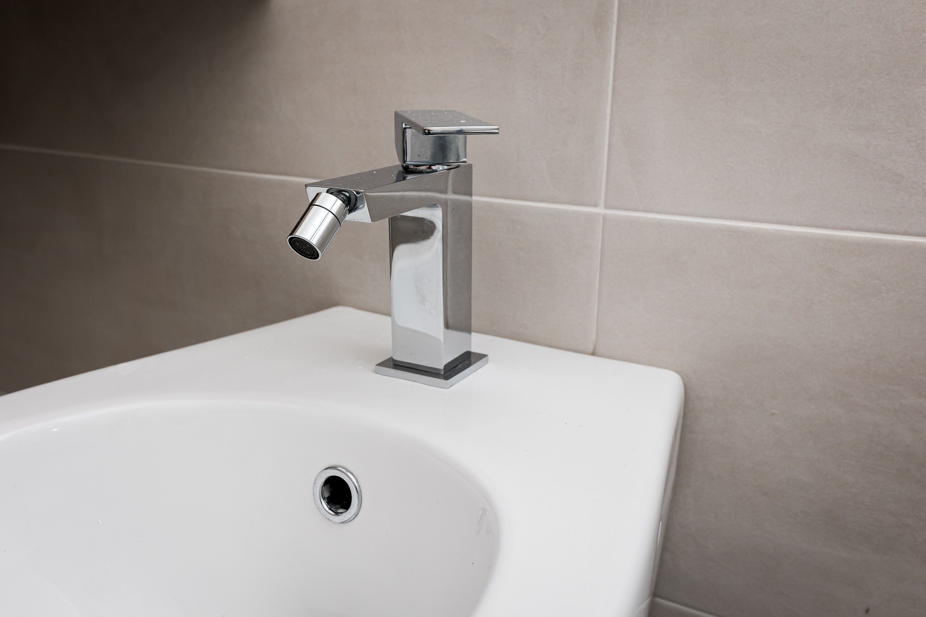 Un lavabo blanco con grifo cromado y un solo orificio de desagüe.