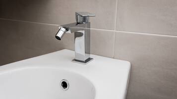 Un lavabo blanco con grifo cromado y un solo orificio de desagüe.