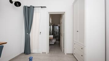 Un pasillo que conduce a un baño con inodoro, ducha y armario.