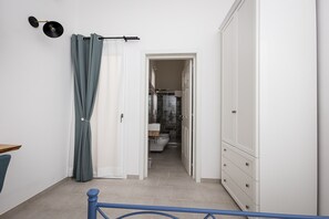 Ein Flur, der zu einem Badezimmer mit Toilette, Dusche und einem Schrank führt.