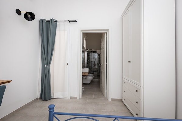 Un pasillo que conduce a un baño con inodoro, ducha y armario.