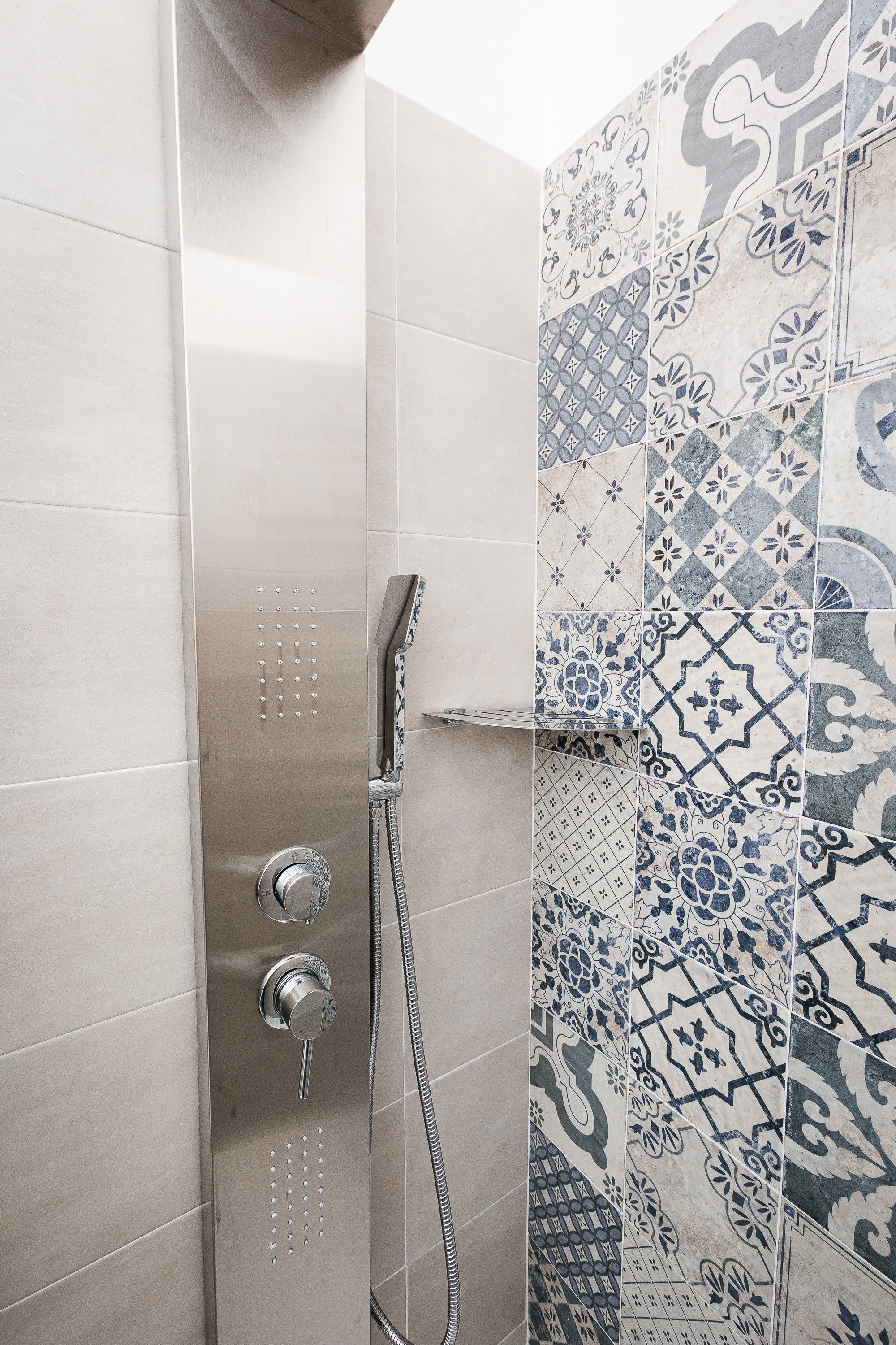 A shower with a handheld showerhead and a wall-mounted control valve.
