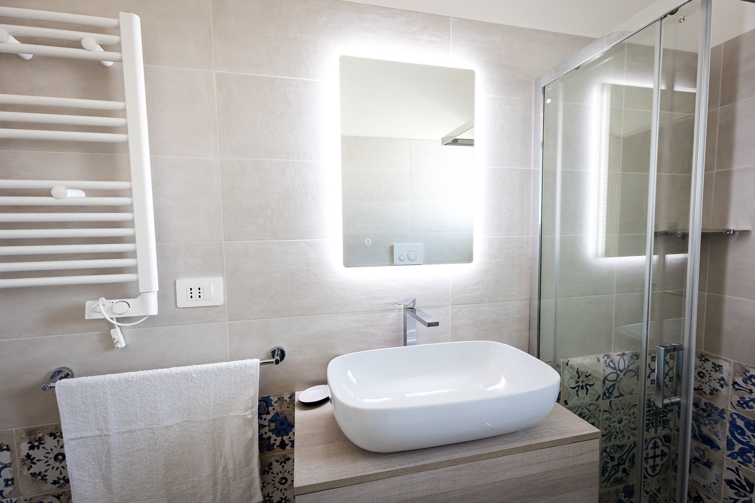A bathroom with a white sink, a glass shower enclosure, and a towel rack.