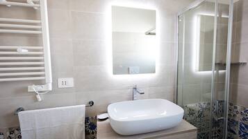 A bathroom with a white sink, a glass shower enclosure, and a towel rack.