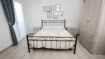 Un dormitorio con cama, mesitas de noche, un armario y una pared adornada con cuadros.