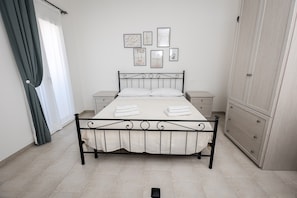 Un dormitorio con cama, mesitas de noche, un armario y una pared adornada con cuadros.