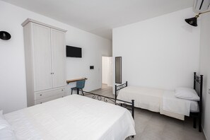 Een slaapkamer met twee bedden, een kledingkast, een bureau, een stoel, een spiegel en een televisie.