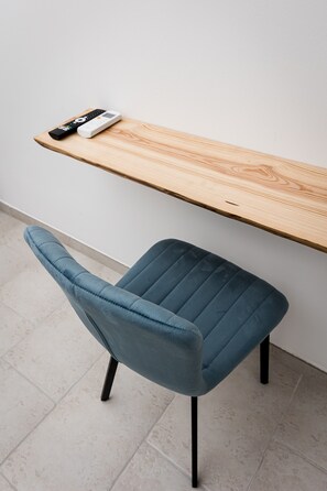 Una silla moderna con asiento y respaldo de tela oscura, junto a un escritorio de madera y un control remoto.