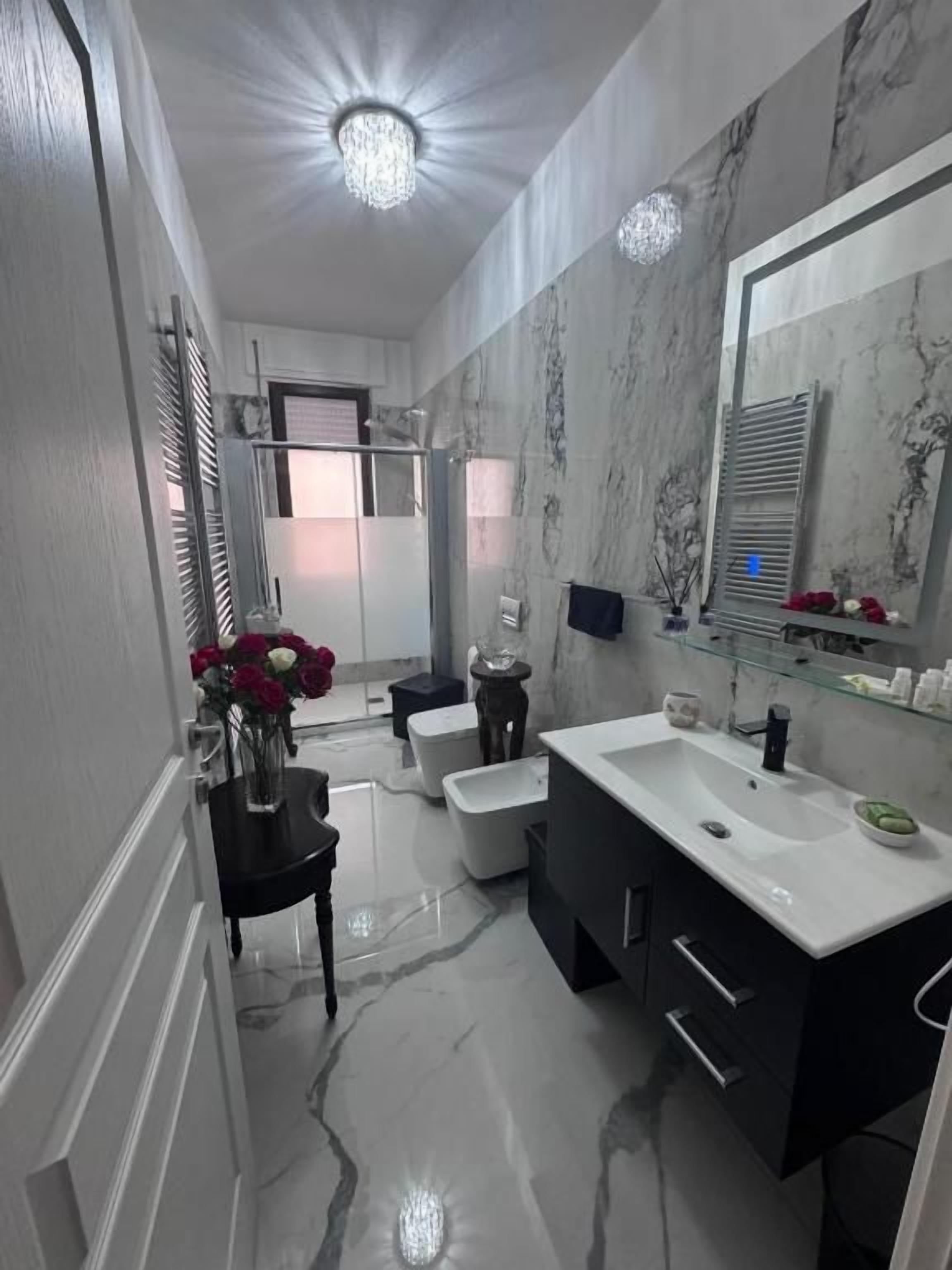 Une salle de bain moderne avec un grand miroir, un lavabo blanc et un meuble-lavabo noir.