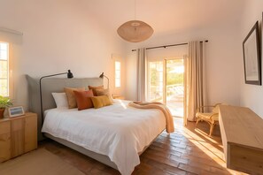 A bedroom with a bed, bedside tables, a lamp, a chair, and a view of the outdoors. - Cosy country house with heatable swimming pool and sea view. (Estói)