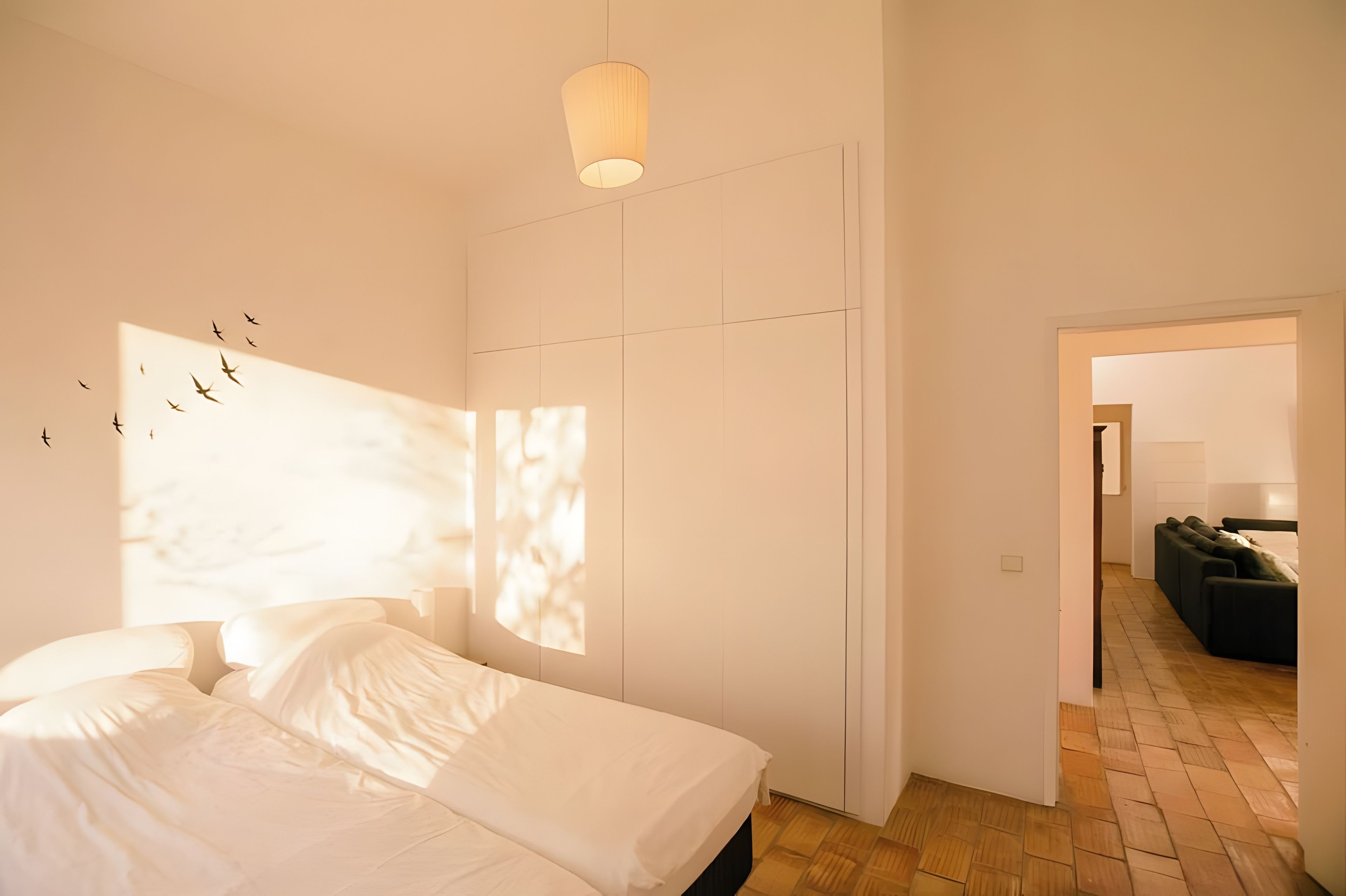A bedroom with a bed, a wardrobe, and a view of a hallway.