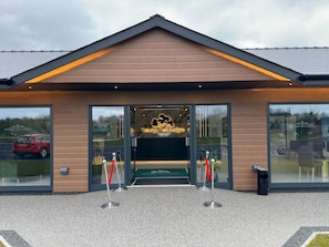 A modern building entrance with a wooden facade, glass doors, and a sign for Nottage Park Lodges. - Nottage Park Lodges (Nottage)
