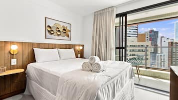 Ein Hotelzimmer mit einem großen Bett, Blick auf die Stadt und einem Holzkopfschild.