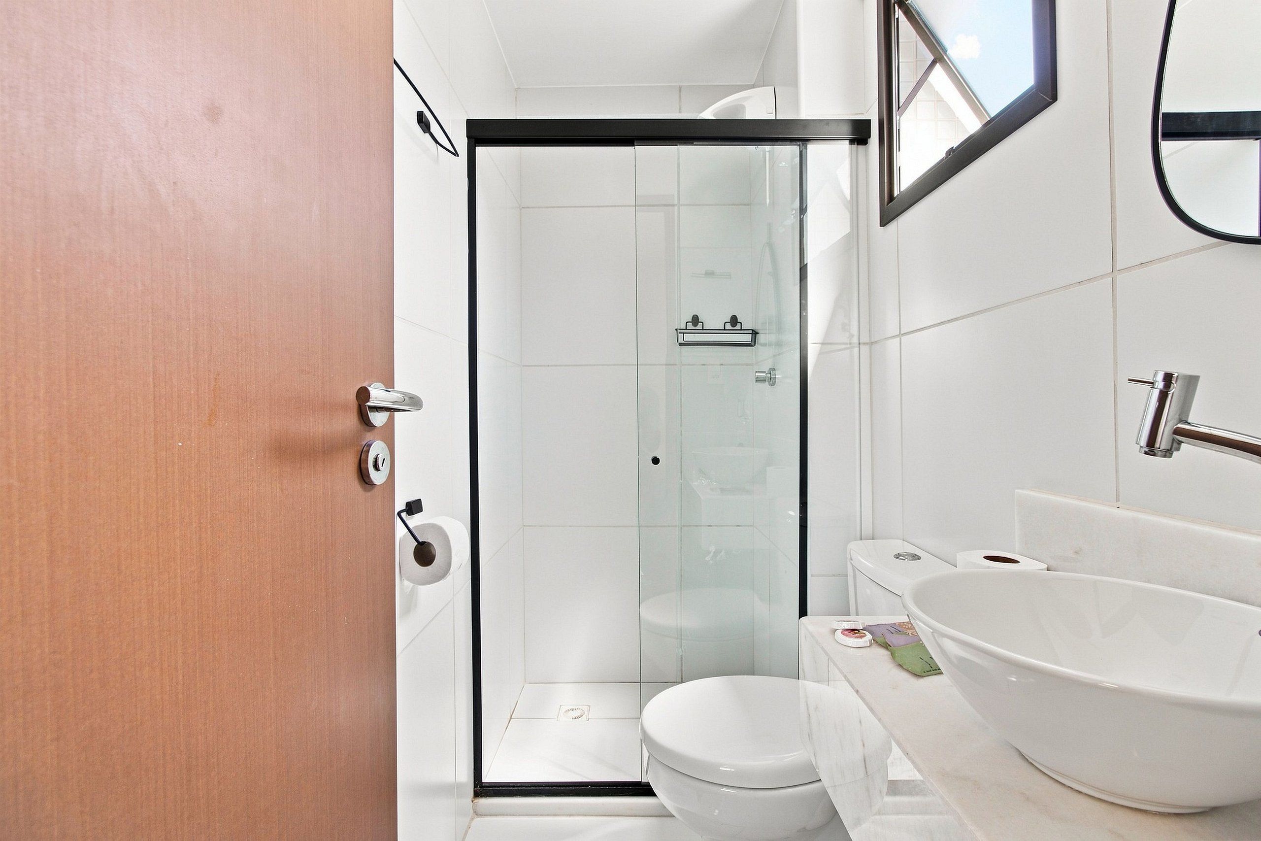 A modern bathroom with a glass shower enclosure, a white toilet, and a large white sink.