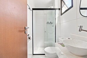 A modern bathroom with a glass shower enclosure, a white toilet, and a large white sink. - ZN Barra 600m From Farol da Barra Beach by Carpediem (Salvador)