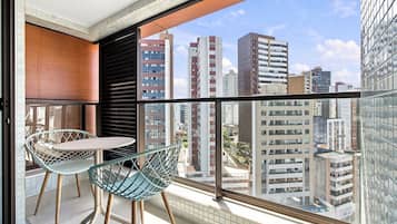 Ein Balkon mit Tisch und Stühlen, Blick auf umliegende Gebäude und ein Fliesenboden.