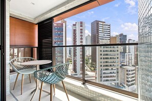 A balcony with a table and chairs, a view of surrounding buildings, and a tiled floor. - ZN Barra 600m From Farol da Barra Beach by Carpediem (Salvador)