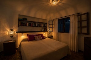 A bedroom with a large bed, two bedside lamps, a bookshelf, and a window with curtains. - Dream chalet in Gran Canaria — right by the sea. Perfect for families & couples. (San Bartolomé de Tirajana)
