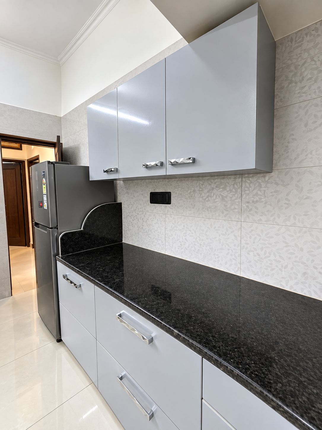 Una cocina moderna con armarios grises, encimera negra y refrigerador empotrado.