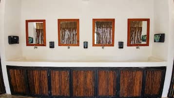 Een badkamer met een lange wastafel, meerdere spiegels en een rieten plafond.