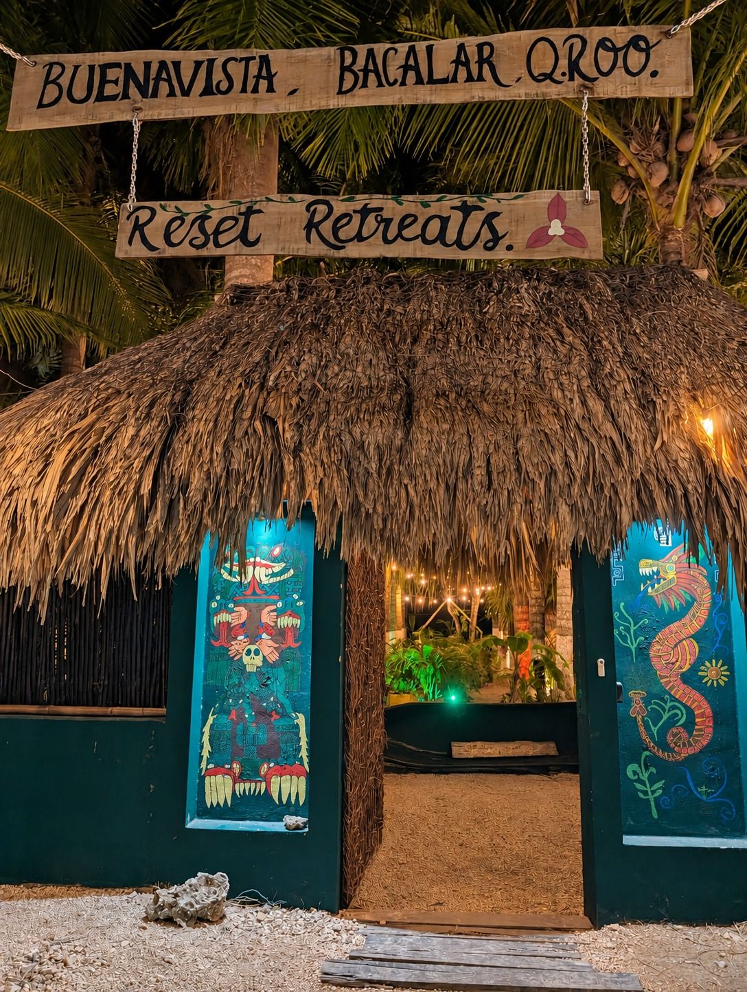 Una estructura de techo de paja con un letrero que dice 'BUENAVISTA, BACALAR QROO. Reset Retreats'.