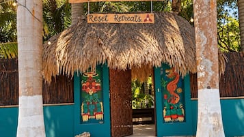 Een gebouw met rieten dak en een bord waarop staat 'Buenavista Bacalar Qroo Reset Retreats A'.