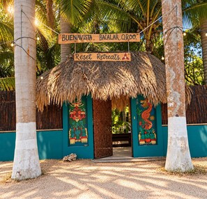 Una estructura de techo de paja con un letrero que dice 'Buenavista Bacalar Qroo Reset Retreats A'.