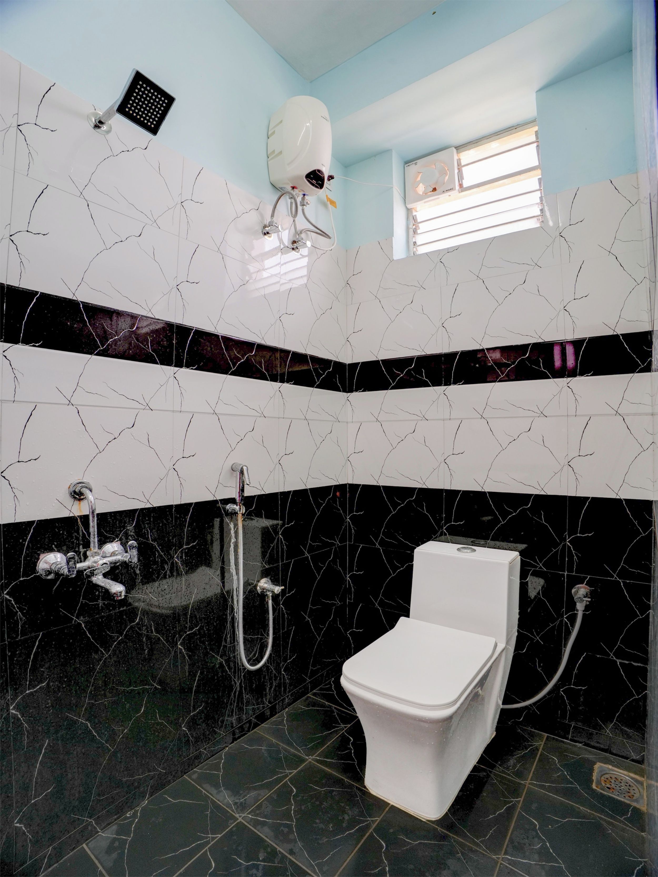 Un baño con inodoro blanco, ducha y calentador de agua instalado en el techo.