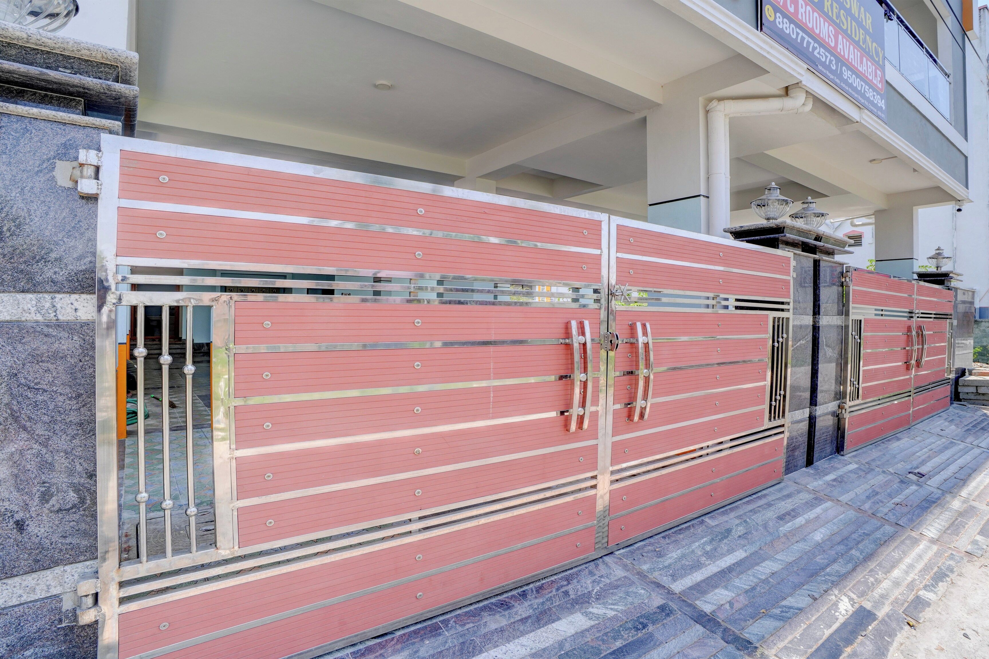 A large, red, metal gate with multiple handles and a glass panel, leading to a building entrance.