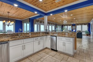A kitchen with white cabinets, granite countertops, and a wooden ceiling. - The Oasis - Seven Bedroom Oceanfront Home with a Private Pool and Hot Tub (Myrtle Beach)