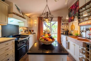 A modern kitchen with a central island, stainless steel appliances, and a variety of utensils and cookware.