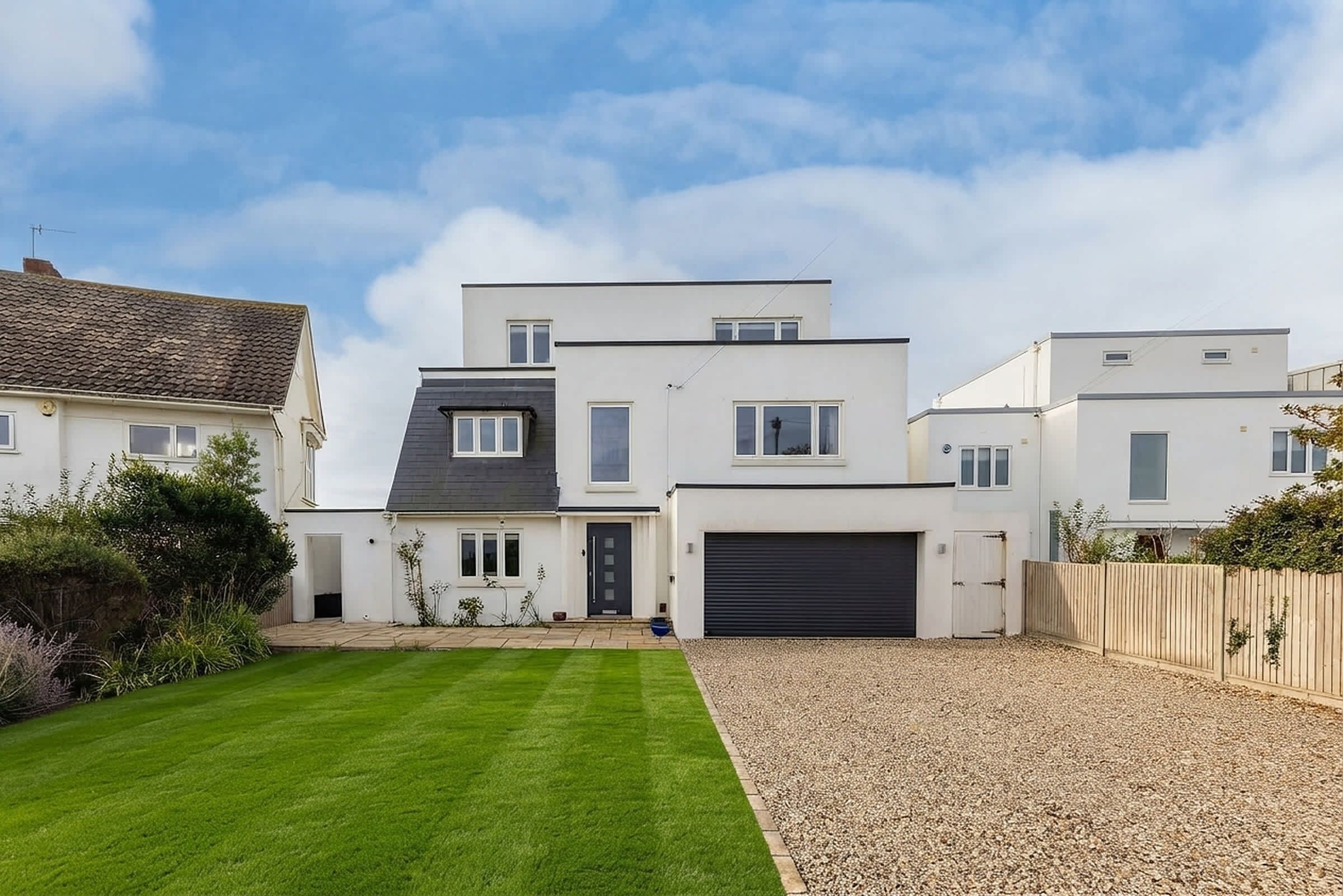 A modern two-story house with a well-maintained lawn and gravel driveway.