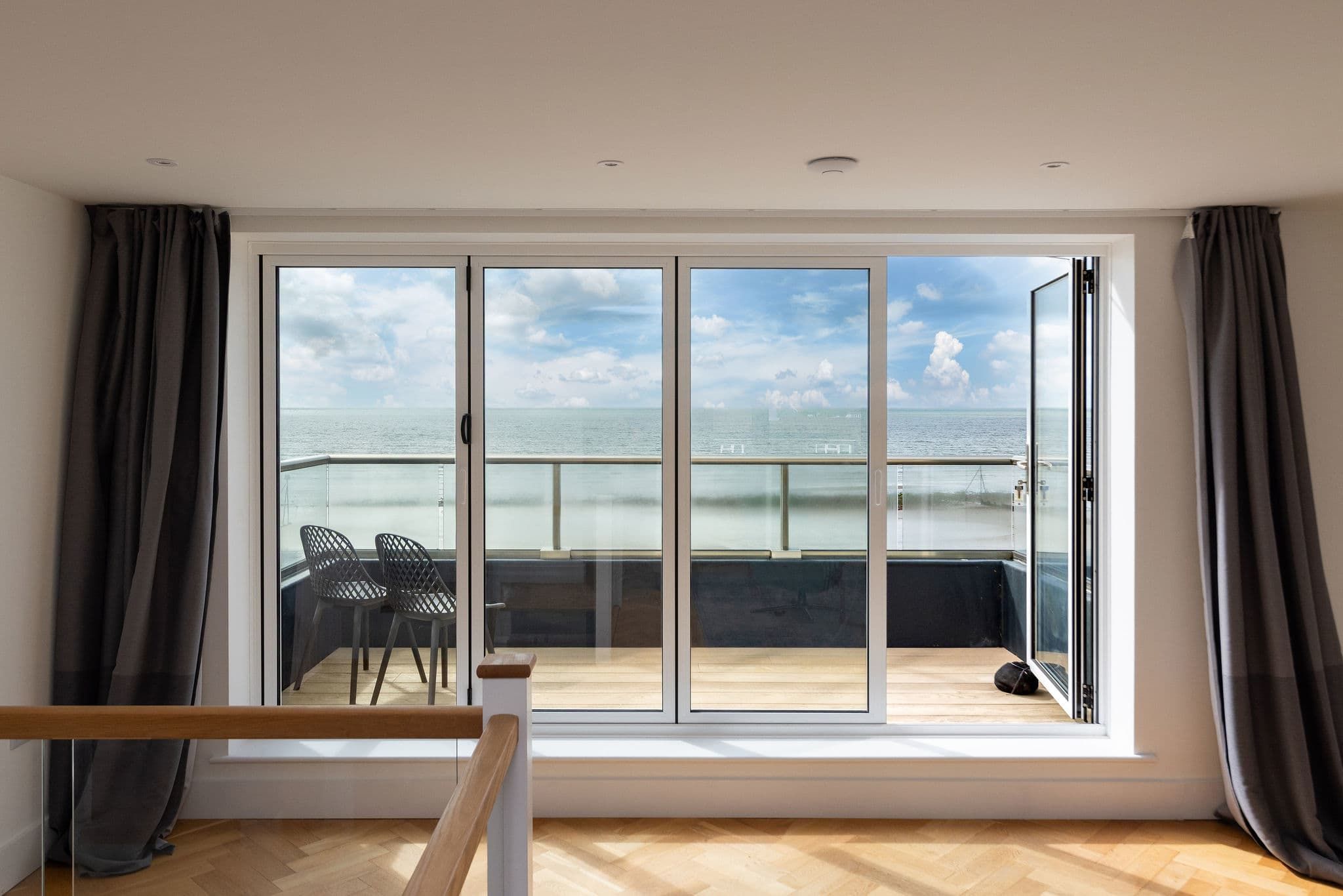 Una habitació amb una àmplia porta corredissa de vidre que dona a un balcó amb vista al mar.