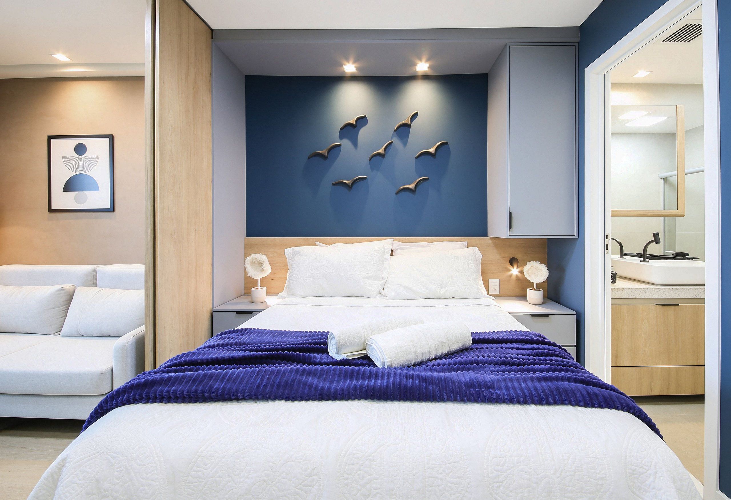 Un dormitorio moderno con una cama, mesitas de noche y una lámpara fijada a la pared.