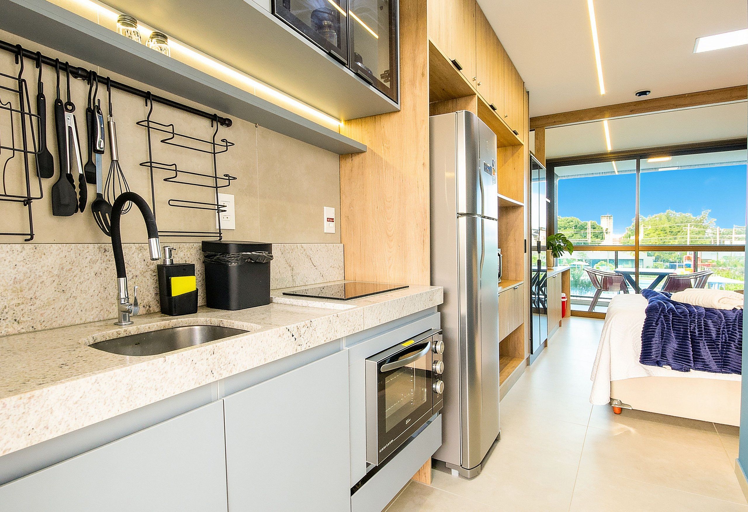 Una cocina moderna con horno empotrado, electrodomésticos de acero inoxidable y ventana con vistas a un balcón.