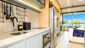 Una cocina moderna con horno empotrado, electrodomésticos de acero inoxidable y ventana con vistas a un balcón.
