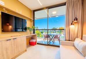 Ein modernes Wohnzimmer mit Fernseher, einem kleinen Tisch mit Stühlen, einem roten Kühlschrank und einem Sofa.