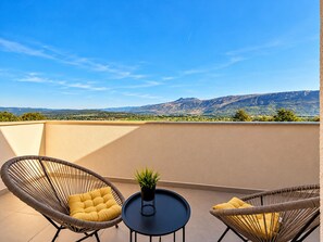 A balcony with two wicker chairs, a small round table, and a potted plant. - Holiday House Mountain View Retreat (Kršan)