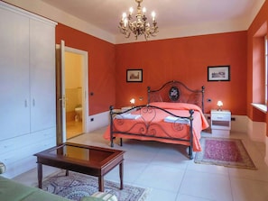 Een slaapkamer met een bed, nachtkastje, kledingkast en een kroonluchter.