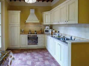 A kitchen with white cabinets, a stove, a microwave, and a sink. - Historic villa with pool and tennis near Lucca (San Ginese)