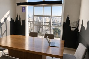 Ein Konferenzraum mit Blick auf die Stadt, ein Laptop auf dem Tisch und ein Fenster mit Jalousien.