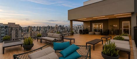 Una terraza en la azotea con mobiliario exterior, plantas en macetas y vistas a la ciudad.